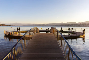 Obraz premium Zurich, Switzerland - January 02, 2020: The circle form public swimming pool at the Lake Zurich in winter season with people walking on it
