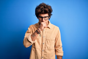 Young handsome man wearing casual shirt standing over isolated blue background feeling unwell and coughing as symptom for cold or bronchitis. Health care concept.