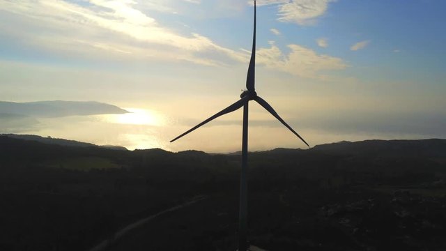 Aerial, tilt up, drone shot, of silhouette windpower turbine at sundown, North Spain