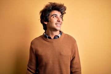 Young handsome man wearing casual shirt and sweater over isolated yellow background smiling looking to the side and staring away thinking.