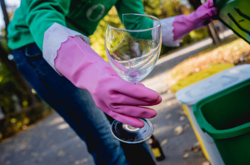 Volunteer girl sorts garbage in the street of the park. Concept of recycling. 