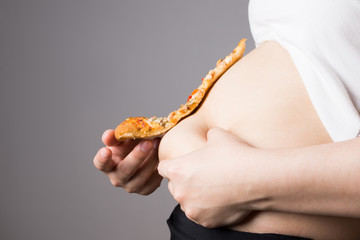 Obraz premium Fat woman with a piece of pizza, unhealthy nutrition concept