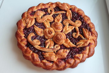 Delicious golden round pie with red cherry and lingonberry filling with dough pattern