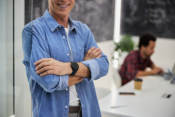 Cheerful gentleman standing by glass door in office