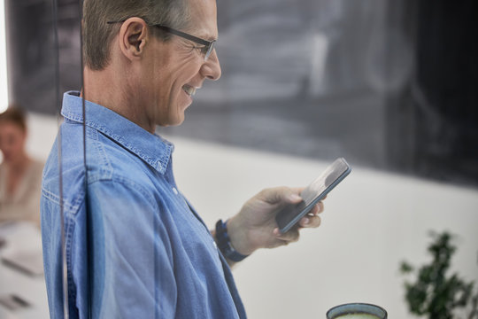 Smiling man in denim shirt using cellphone - Powered by Adobe