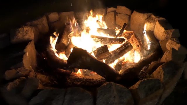 A handheld shot of a stone fire pit at night featuring multiple angles.