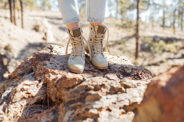 Woman standing on the stones, hiking on a rocky land, close-up on legs in trekking shoes