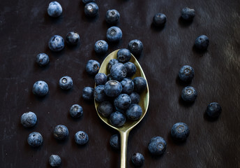 metal spoon whit blueberries on a dark base