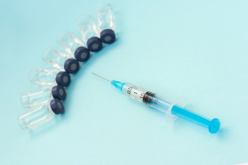 Glass medicine bottles with injection fluid with blue aluminium caps and syringe for vaccination. Cancer, painand diabetes treatment, pharmaceutical medicine concept .