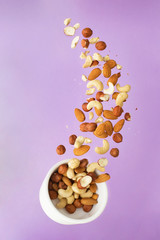 Flying nuts on a purple background: almonds, cashew and hazelnat