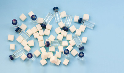 Sugar addiction, insulin resistance, unhealthy diet, sugar cubes and bottles of insulin on blue...