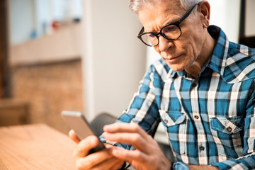 Obraz na płótnie Canvas Adult male sitting at workplace with smartphone