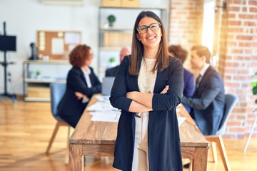 Group of business workers smiling happy and confident working together in a meeting. One of them, standing with smile on face looking at camera at the office.