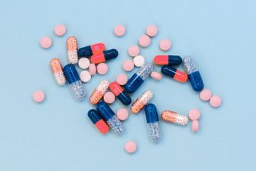 Heap of colorful pills, tablets, capsules on blue background. Drug prescription for treatment medication health care concept wth copy space.