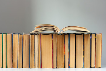 Open hardback book, diary, fanned pages on stack of books on white table in library. Books stacking. Back to school concept. Copy Space. Education learning background.