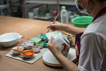 painting chicken patternon on white ceramic bowl , the famous chicken bowl and ceramic of Lampang  in Thailand.
