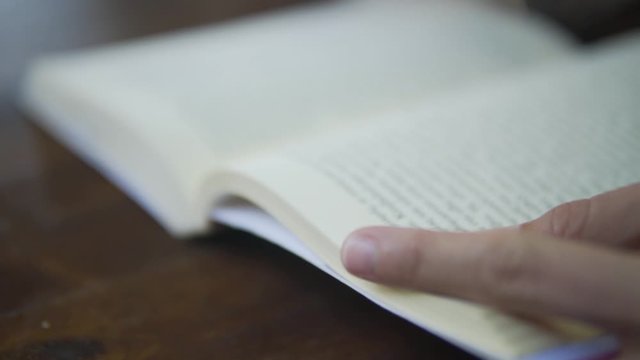 close up of caucasian person reading a book while sitting on table, relaxing with a book, personal time , free time studying  b roll