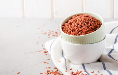 Uncooked red  rice Dev-zira in bowls on the table, light background, free space for text. Rice for Uzbek pilaf