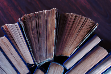 Old and well used hardback books or text books in a book shop or library. Many Books Piles. Hardback books on wooden table top view. Back to school background with copy space.