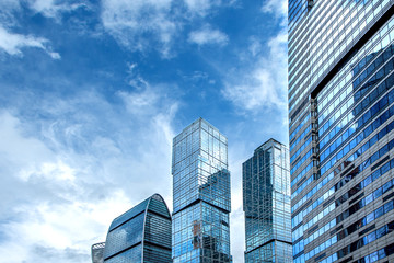 Obraz premium Low angle view of tops of modern new business corporate buildings against the blue sky.