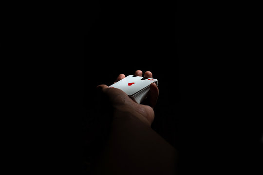 hand hold a deck of cards ace of hearts with poker top on a black background copy space. close up