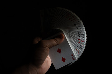hand hold a fan from a deck of poker cards on a black background copy space. close up