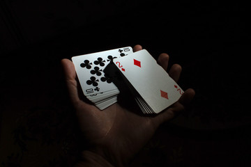 hand hold a deck of cards one hand shuffle volt poker on a black background copy space. close up