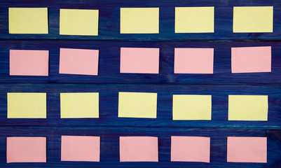 yellow and pink pieces of paper for notes on a blue wooden background