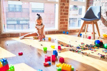 Young beautiful blonde girl kid enjoying play school with toys at kindergarten, smiling happy playing with cars at home