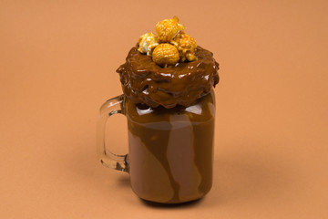 Chocolate milkshake with whipped cream, cookies, waffles, served in glass mason jar. 
