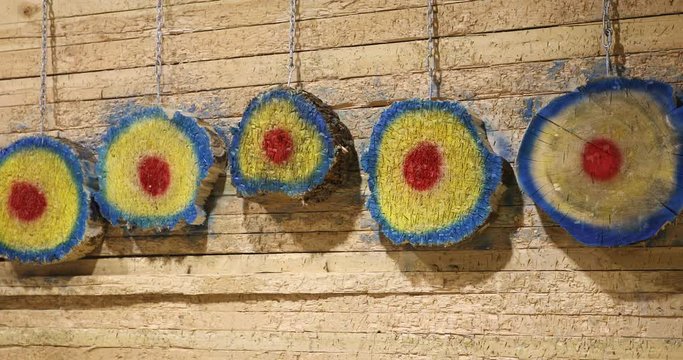 Bullseye target Axe at wooden slow motion HD. Sport and competition where a sharp axe and other metal weapons are thrown at a bulls eye wooden target for fun and score. Family friend recreation.