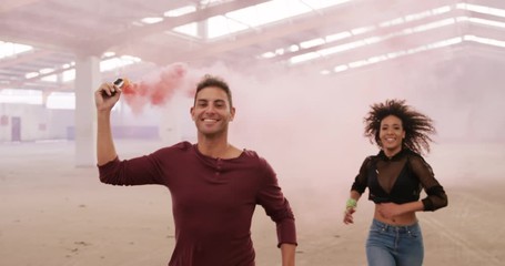 Dancers in an empty warehouse holding smoke grenade