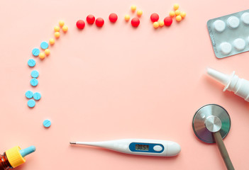 multicolored pharmaceutical pills thermometer, bottle, phonendoscope on a pink background. Copy space. the concept of health. concept  of life. assorted medicines. bright pills. coronavirus