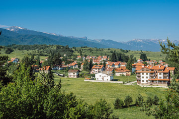 Fototapeta na wymiar A picturesque summer landscape from Bulgaria, the Bulgarian mountain village of Madzhare against the background of Rila Mountain and clear blue sky.