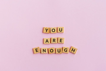 Inspirational quotes - You are enough text wood blocks. Pink background.