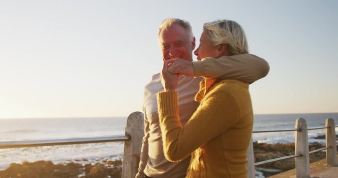 Senior couple embracing each other alongside beach