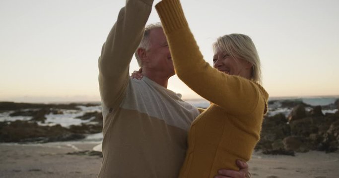Happy senior couple dancing at beach