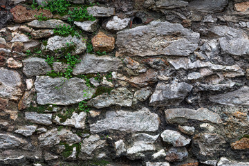 wall composed of large exposed stones with grey cement