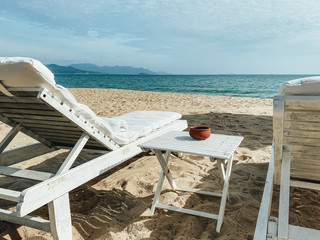 White soft sun loungers on the shore of a sandy sea beach. Tropical resort