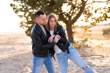 Happy and cute adorable adult couple of millennial hipsters, man with woman girlfriend walking, have fun play, laugh,smile and jump on sunset at desert
