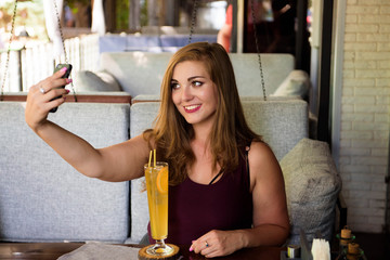 A woman of plus size enjoying life, drinking lemonade. A young lady with natural beauty. XXL model.
