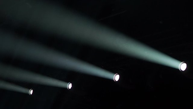 Showtime moving heads i a dark room projecting a beam of light through the smoke and creating a beam in the particles while moving up and down, with copy space.
