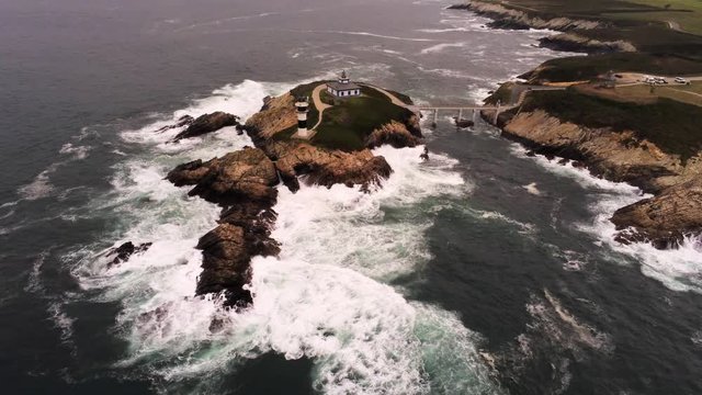 Beautiul aerial drone view of Pancha Island in Galicia with  lighthouse and bridge over the strong waves washing the rocks on the seaside