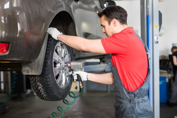 Auto mechanic in his workshop changing tires or rims at service