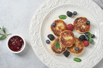 Cheesecakes with berries. Cheesecakes served with fresh berries of raspberries, blueberry, blackberries and mint. Light background. View from above. Close-up.