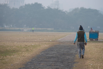 Local Indian people are walking in a dry grass field in a misty winter morning in natural background. Indian lifestyle.