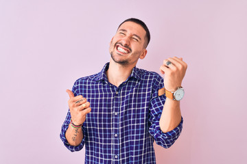 Fototapeta premium Young handsome man standing over isolated background very happy and excited doing winner gesture with arms raised, smiling and screaming for success. Celebration concept.