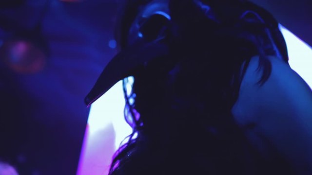 Mysterious Masked woman dancing at night in the glowing neons of the underground night club. She is strange and sexy. Captured in 4K under the beautiful colors.