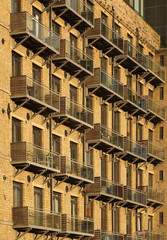 perspective view of the facade of a large old stone mill building converted into apartments with modern glass balconies