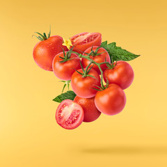 Fresh ripe red tomatoes flying in the air isolated on yellow background.